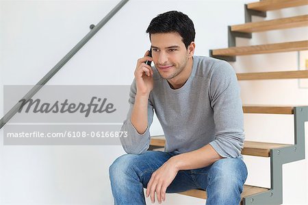 Man sitting on stairs and talking on a mobile phone