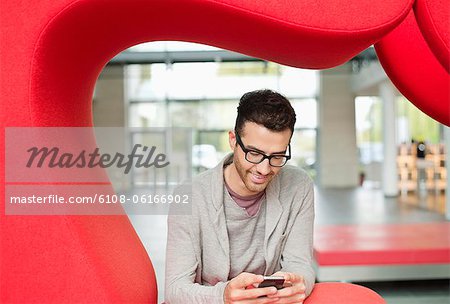 Businessman text messaging and smiling in an office
