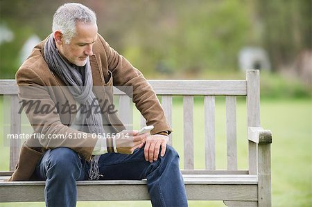 Mann von SMS-Nachrichten auf dem Handy in einem park Mann von SMS-Nachrichten auf dem Handy in einem park