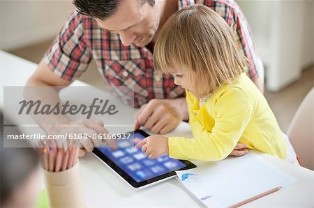 Man teaching digital tablet to his daughter Man teaching digital tablet to his daughter