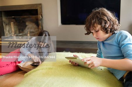 Garçon et une fille à l'aide de gadgets électroniques à la maison