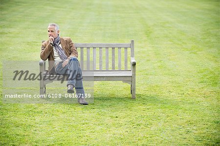 Mann auf einer Bank sitzen und denken in einem park