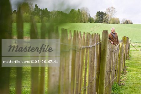 Homme debout de clôture dans un champ