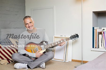 Portrait d'un homme heureux en jouant une guitare