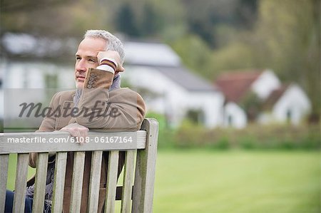 Homme assis sur un banc et penser dans un parc