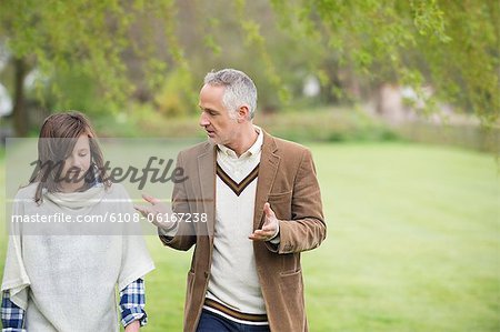 Man discussing with his daughter during walk in a park