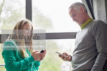 Homme et fille à l'aide de leur téléphone mobile