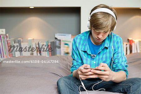Teenage boy listening to music on iPod at home