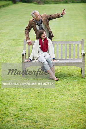 Man sitting with his daughter on a bench and pointing in a park