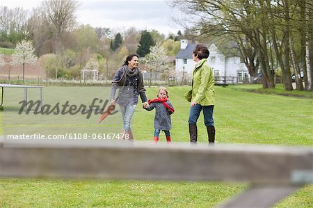 Girl walking with her mother and grandmother in a lawn