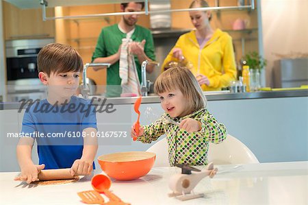 Enfants avec leurs parents dans le fond de cuisson dans la cuisine