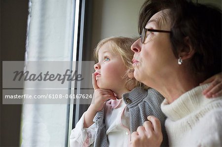 Woman with her granddaughter looking through a window