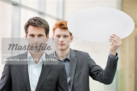 Portrait d'un homme d'affaires avec son collègue tenant une bulle de dialogue derrière lui