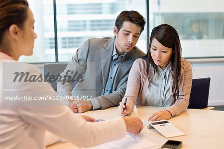 Couple signing documents with business executive