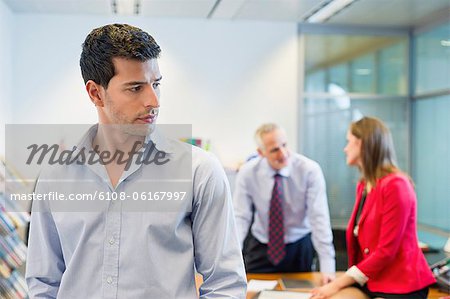 Male executive listening to his colleagues conversation in an office