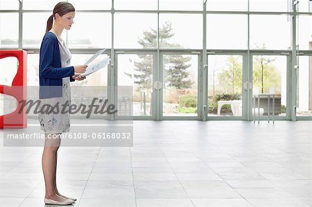 Businesswoman holding documents and standing in an office lobby