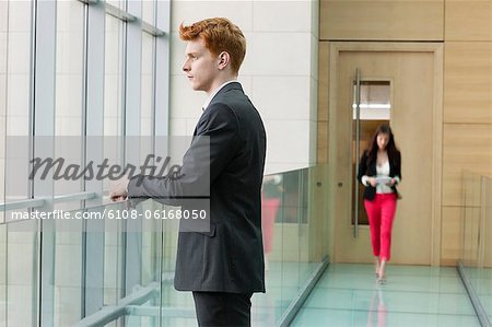 Businessman looking through glass window in a corridor