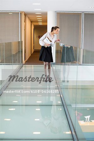 Businesswoman peeking through glass in a corridor