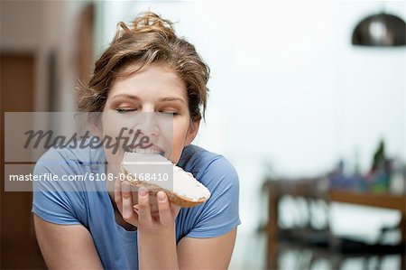 Close-up of a woman eating toast with cream spread on it