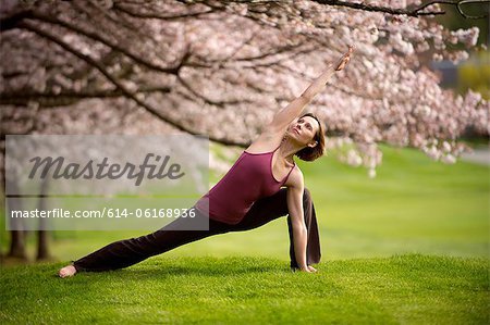 Woman in side angle yoga position under cherry tree