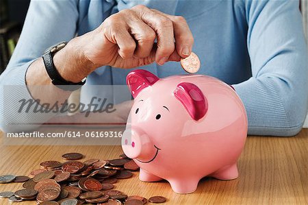 Senior woman inserting coins into piggybank