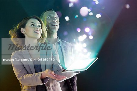 Businesspeople looking at lights coming from digital tablet