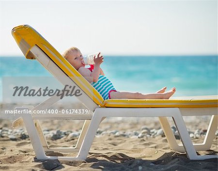 Baby laying on sunbed and drinking water