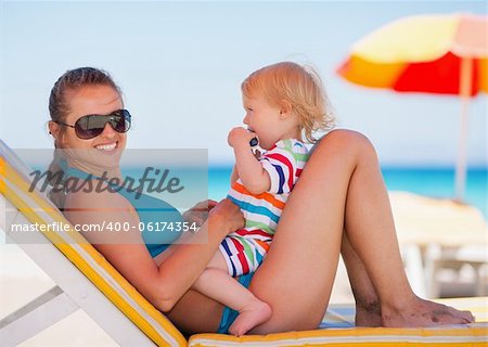 Portrait of happy mother and baby on sun bed
