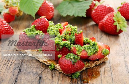 Strawberry bruschetta with pesto on a wooden table.