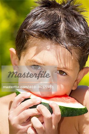 wet boy with watermelon in the garden after swimming