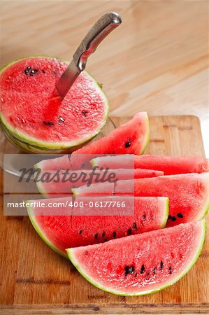 fresh ripe watermelon sliced on a  wood table with knife