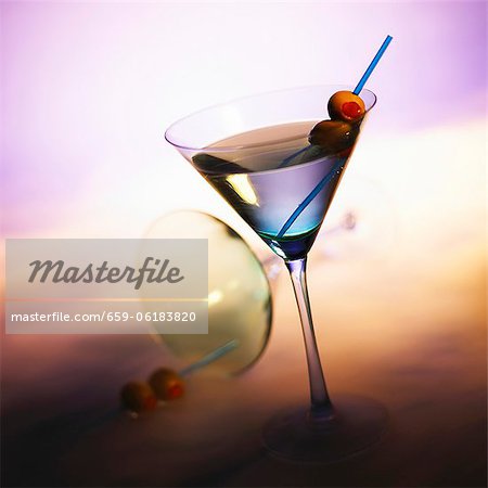 Vodka Martini with Olives; Tipped Martini Glass in Background Vodka Martini with Olives; Tipped Martini Glass in Background