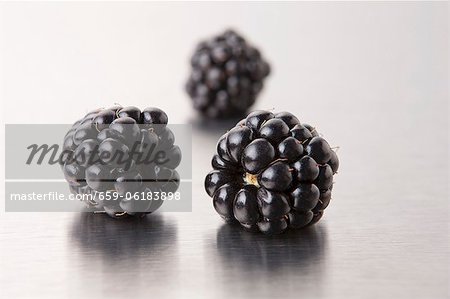 Three blackberries on a metal surface (close-up)