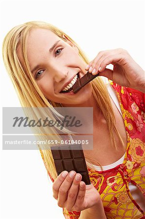 Une jeune femme à mordre un morceau de chocolat noir