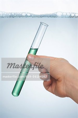 Eine Hand hält ein Reagenzglas von Spülmittel Eine Hand hält ein Reagenzglas von Spülmittel