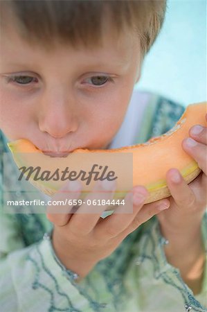 Small boy eating a slice of melon