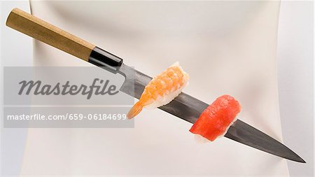 Nigiri saumon et crevettes sur un couteau à sushi Nigiri saumon et crevettes sur un couteau à sushi