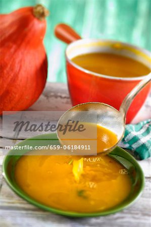 Pumpkin soup being poured into soup plates