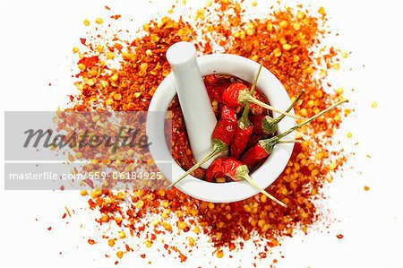 Dried chilli peppers and chilli flakes in a mortar