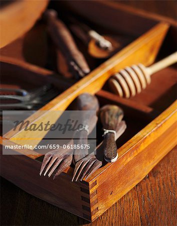 Alte Holzlöffel und Gabeln mit alten Werkzeugen in einer Holzkiste