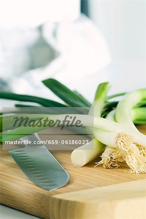 Spring onions and a knife on a wooden board