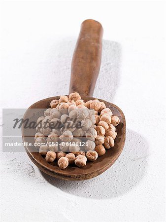 A pile of chickpeas on a wooden spoon