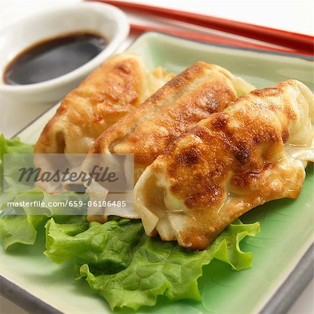 Drei Potstickers mit Stäbchen und Sojasauce