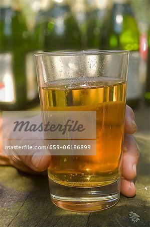 A hand holding a glass of apple wine