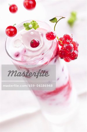 Redcurrants falling into a layered yogurt dessert