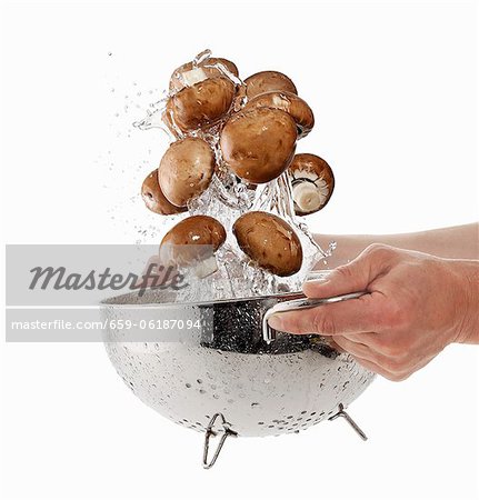 Brown mushrooms being washed in a sieve