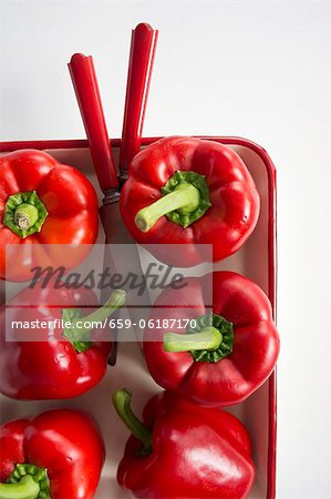 Red peppers in a roasting dish with a knife