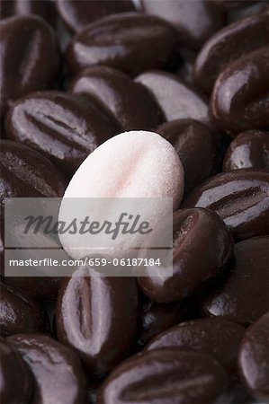 Un grain de café de sucre rose sur un tas de vrais grains de café