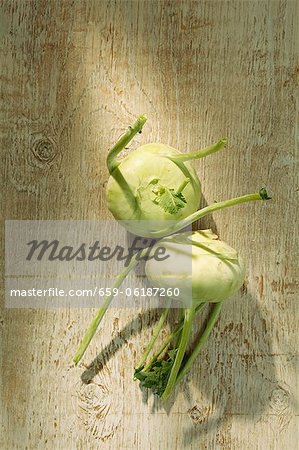 Two kohlrabis on a wooden surface