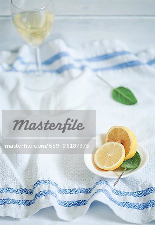 Un verre de vin blanc sur une serviette de cuisine, de sauge et de citron frais